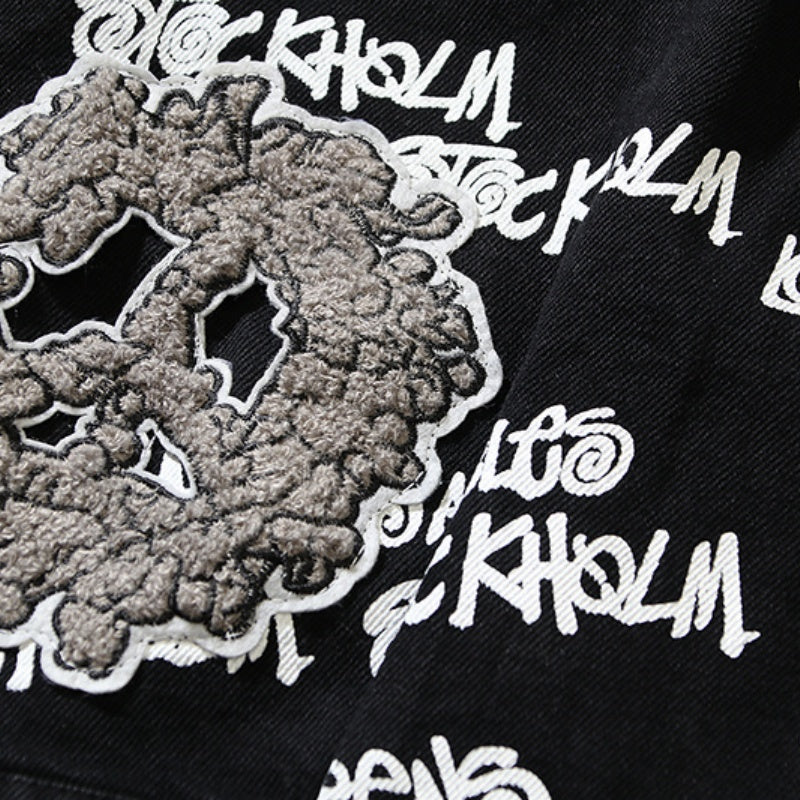 American-style baseball jacket Stu x Tears American High-Street Collaboration: Denim Jacket Featuring All-Over "Barrage" Text Print and Embroidered Cotton Boll Motifs.